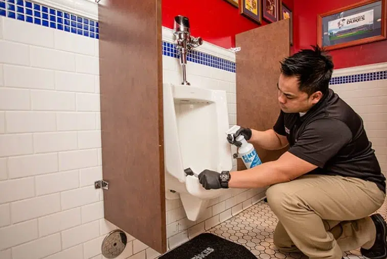 5 Reasons Public Restrooms Can Be a Complete Turnoff Fikes employee cleaning a urinal | public restrooms