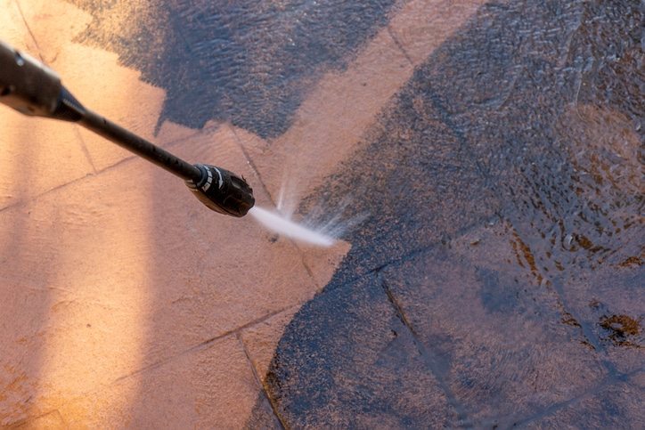 Cleaning dirty backyard paving tiles with pressure washer cleaner. Spring clean up