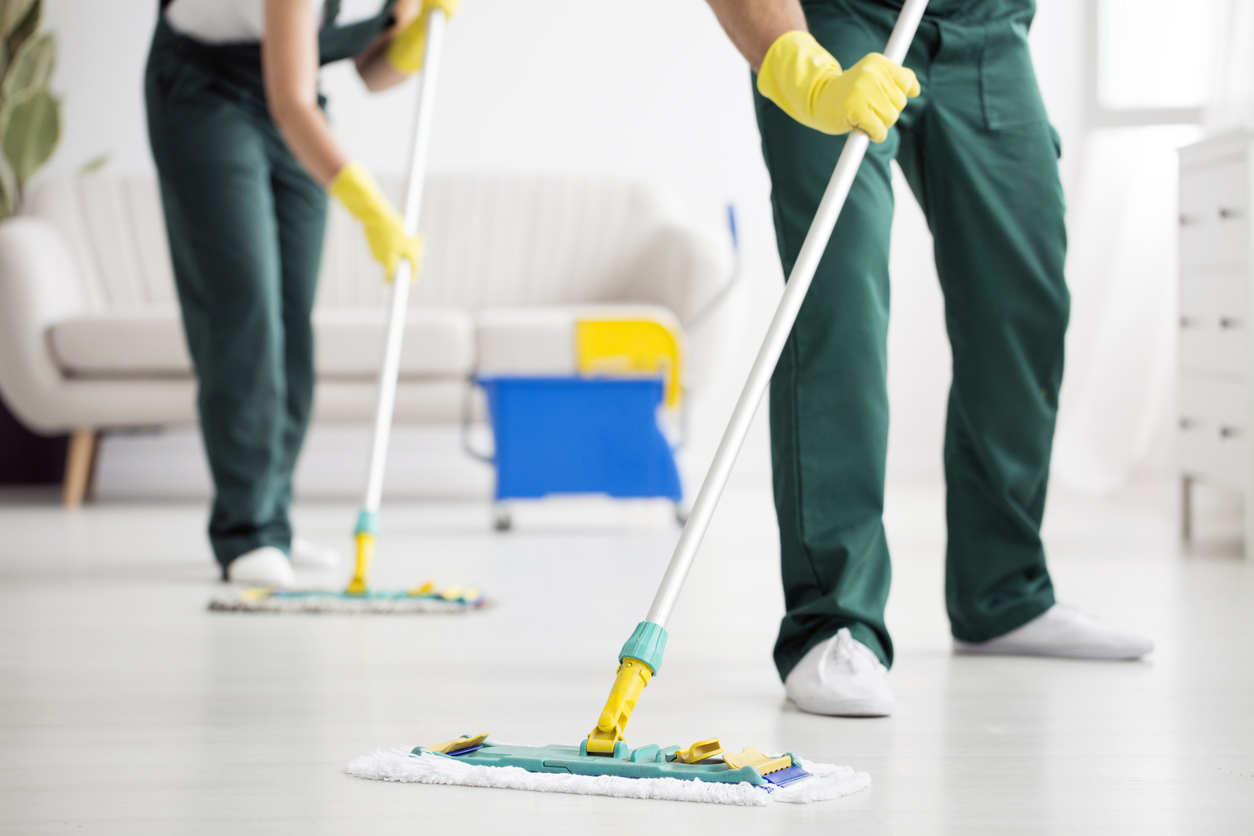 Cleaning team wiping the floor using mops in the flat