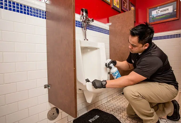 The Hidden Germ Zones: Why Restrooms Need More Than Basic Cleaning Man cleaning a public restroom toilet