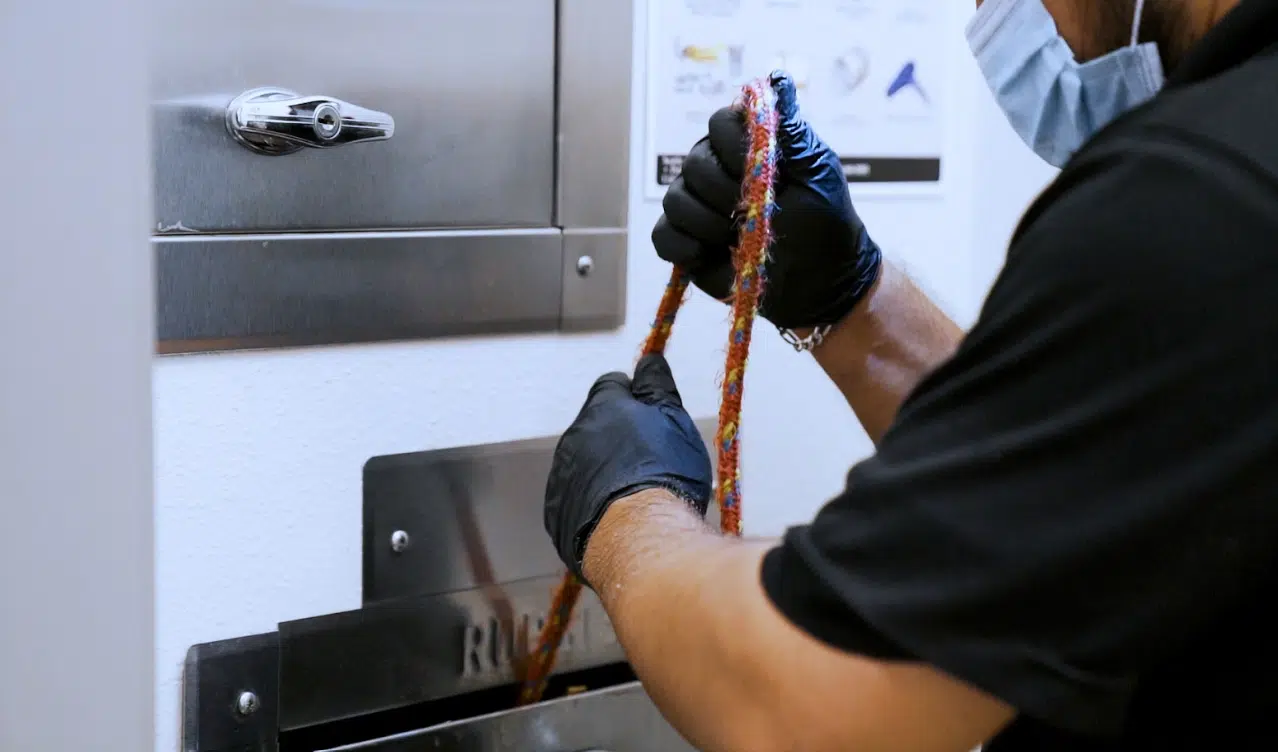 A man doing trash chute maintenance using a rope tool