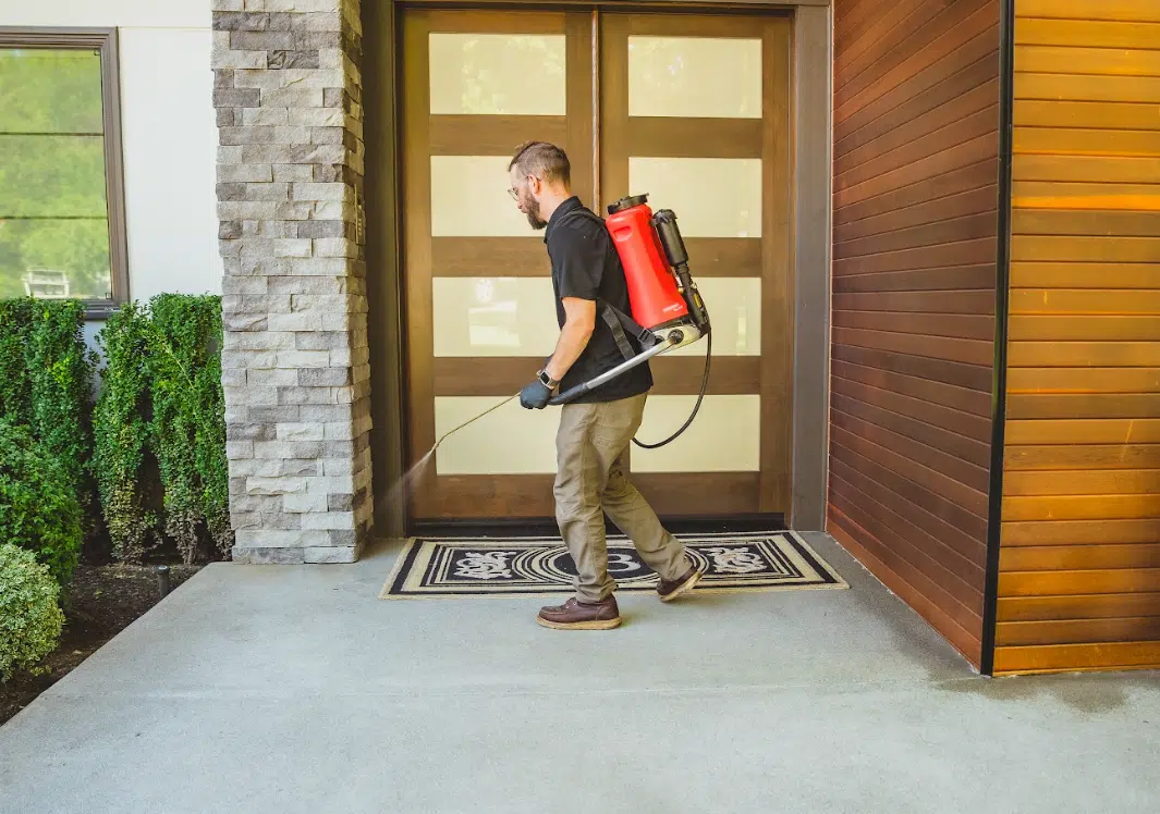 Rodent Season Never Ends: Year-Round Rodent Prevention for Seattle & Multi-Family Buildings Nationwide A man spraying chemicals around a door for rodent prevention