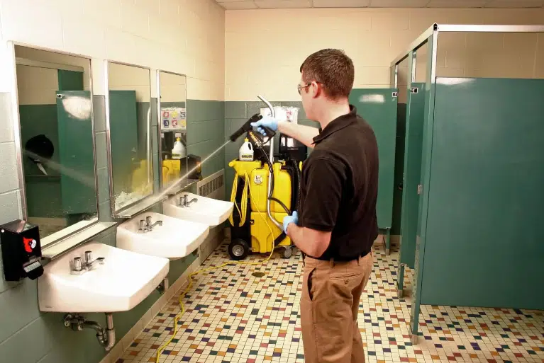 The Business Science of Long-Lasting Restroom Freshness Fikes employee cleaning a public restroom, spraying it down