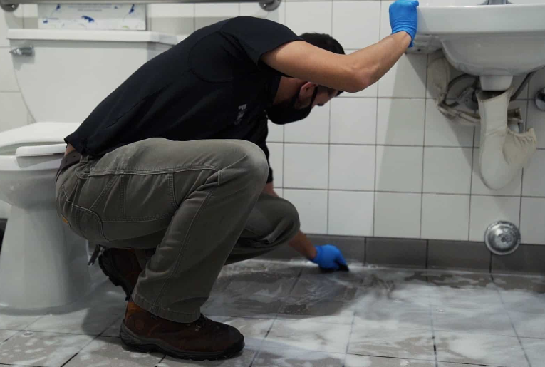Why Specialized Restroom Sanitation Is Non-Negotiable for High-Volume Venues & Entertainment Facilities Man cleaning a public restroom floor