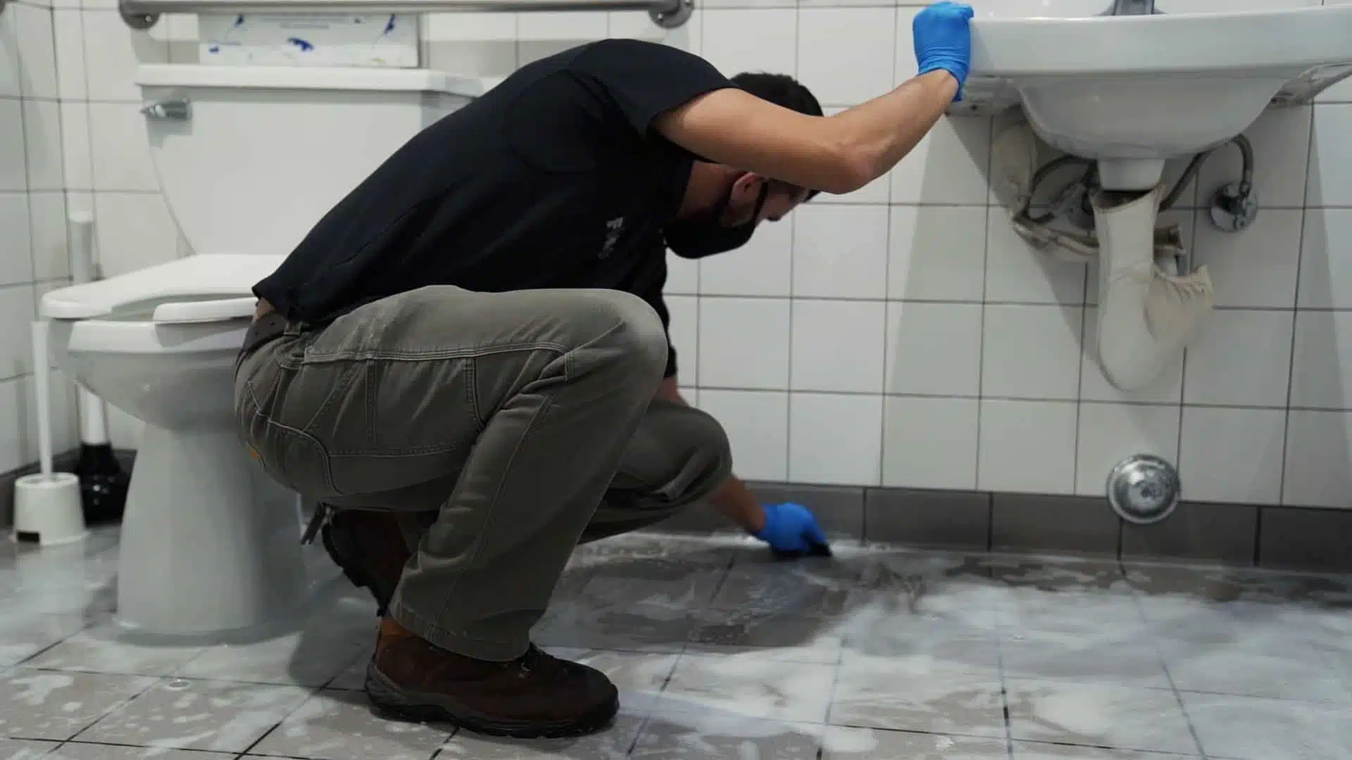 Commercial Restroom Sanitation vs. Basic Janitorial Mopping: What's the Difference? man kneeling down scrubbing a restroom floor