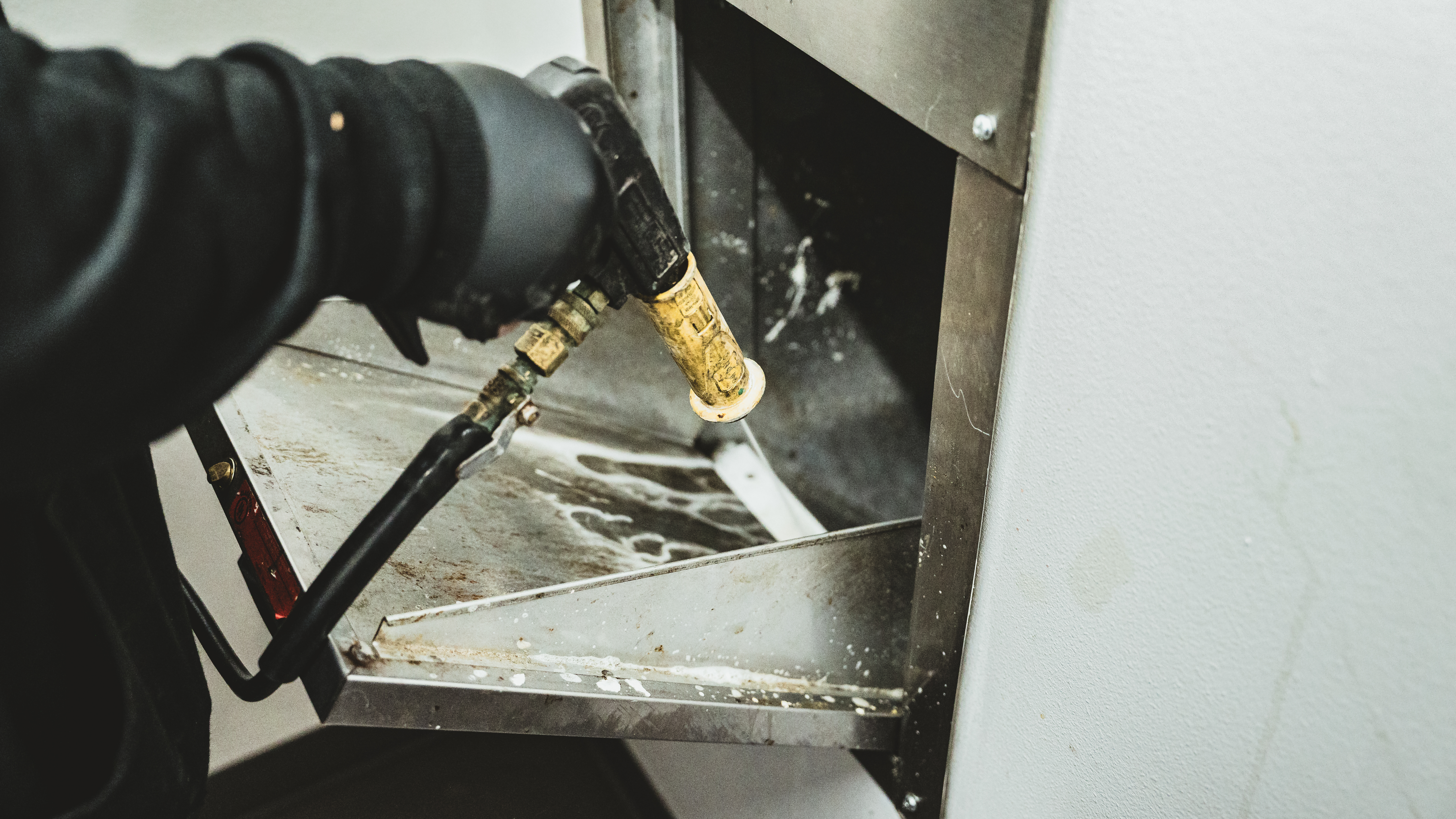 Why Your Apartment Building Smells Like a Trash Chute in August (And How to Fix It) worker spraying down a dirty trash chute