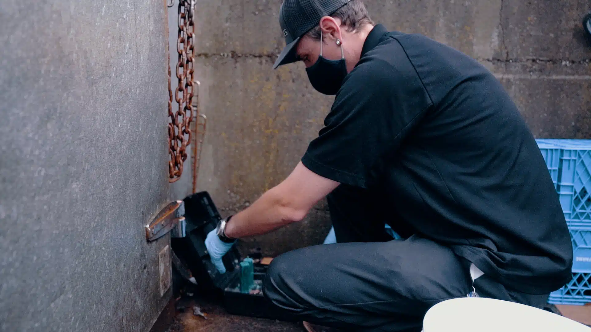 The Ultimate Facility Manager's Commercial Pest Exclusion Guide for Fall Worker setting up a pest control device on the outside of a building